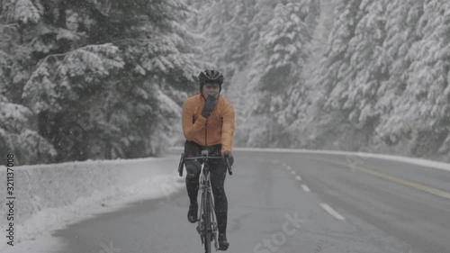 Determined female athlete riding bicycle on highway during snowfall