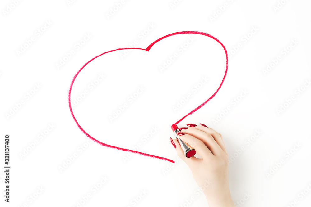 Beautiful female hand with trendy red manicure drawing heart with vibrant red lipstick on white background. Creative trendy flat lay with space for text. Backdrop for your design. Love and celebration Beautiful female hand with trendy red manicure drawing heart with vibrant red lipstick on white background. Creative trendy flat lay with space for text. Backdrop for your design. Love and celebration