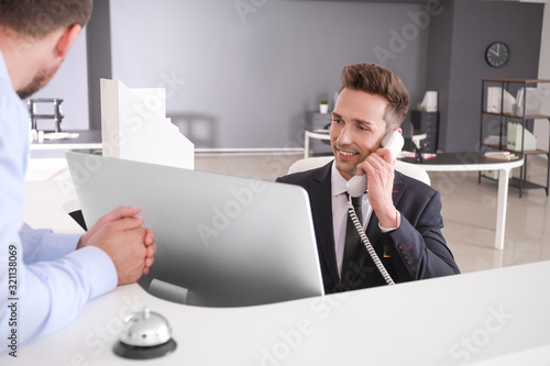 Quadro em tela Male receptionist working with visitor in office
