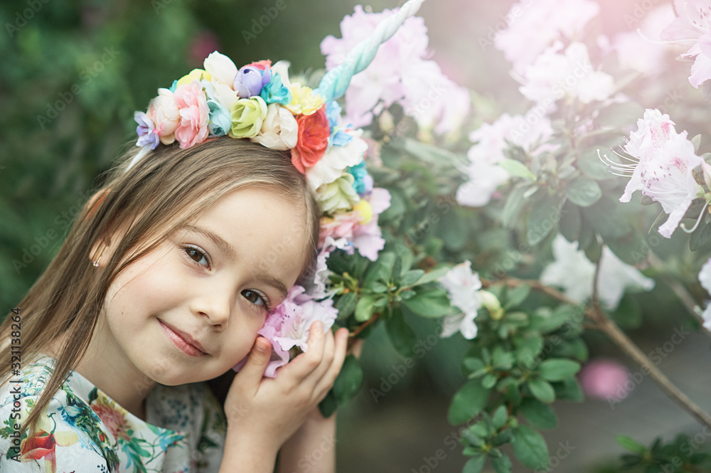 Naklejka premium Fantasy little girl with rainbow unicorn horn with flowers in azalea park