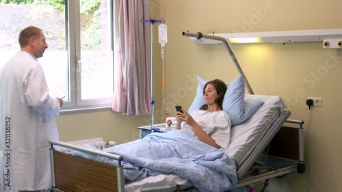 Handheld shot of patient using mobile phone in hospital bed before doctors making rounds