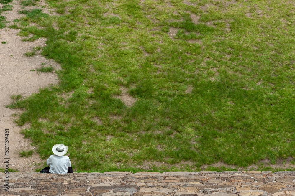 Obraz premium Man with a hat looking out over a green field