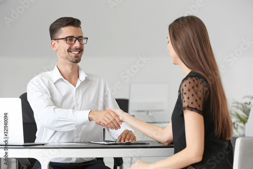 Bank manager shaking hands with woman in office