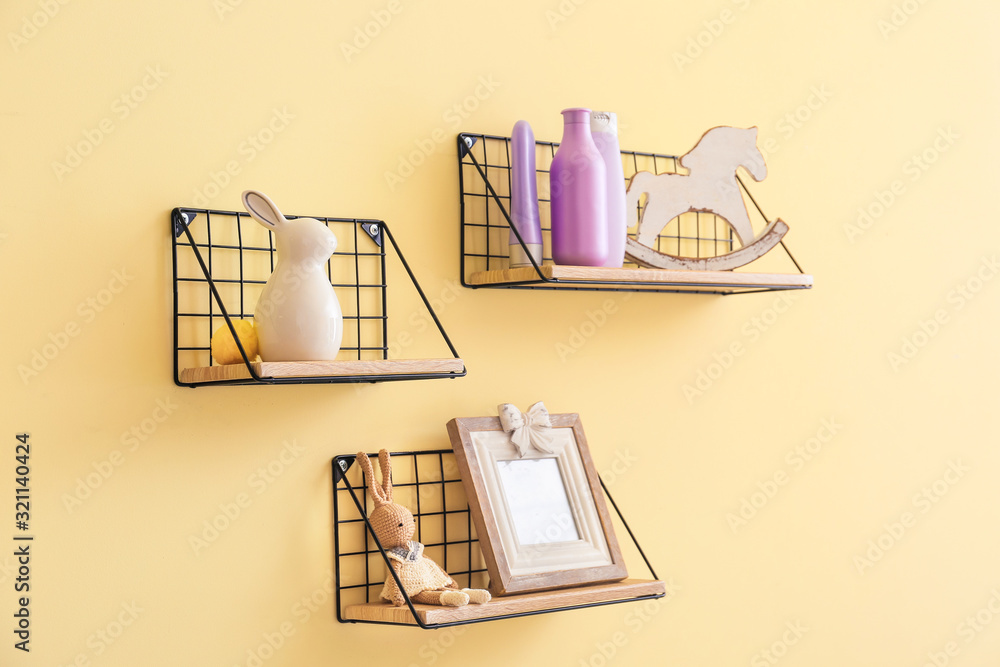 Shelves with baby cosmetics and toys on color wall Shelves with baby cosmetics and toys on color wall