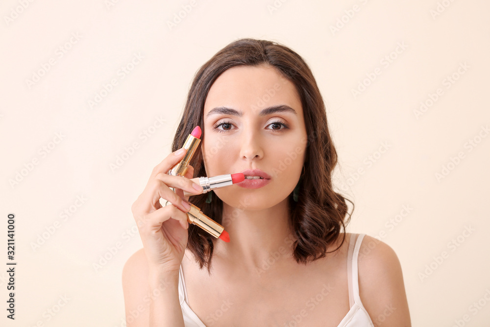 Beautiful young woman with lipsticks on light background Beautiful young woman with lipsticks on light background
