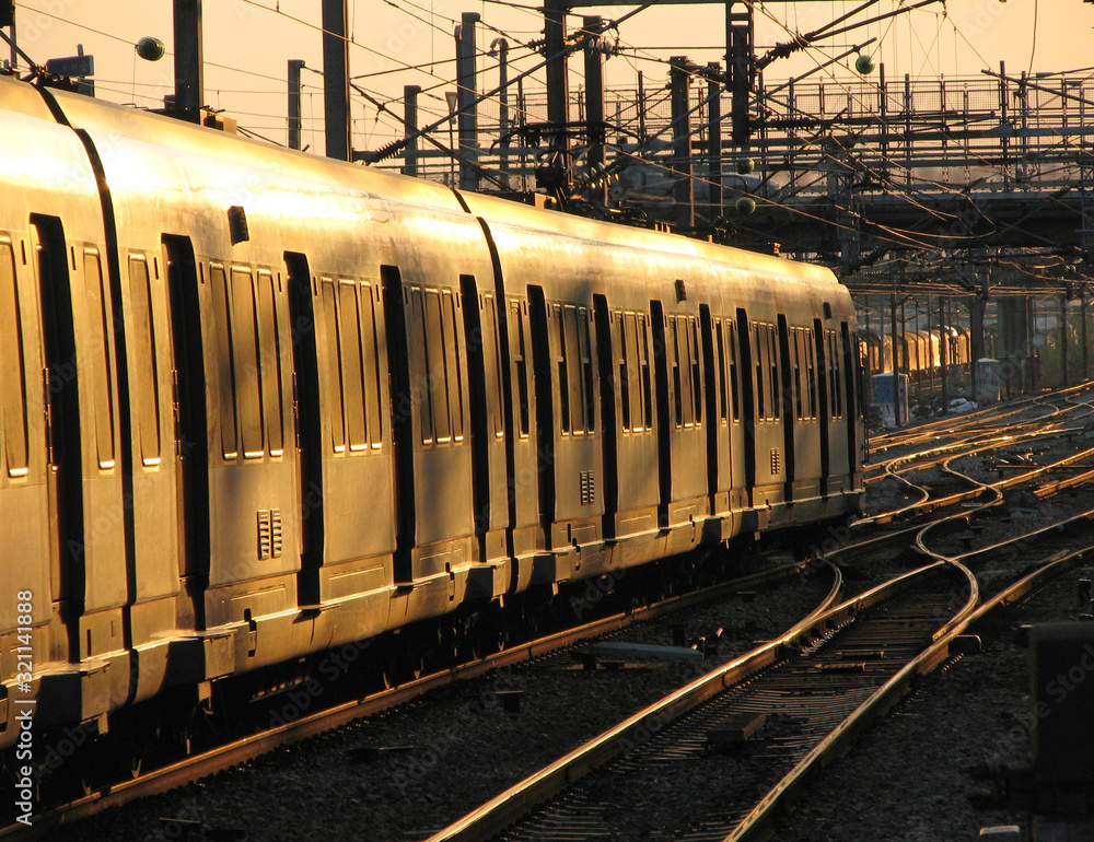 Fototapeta premium Passenger train moving slowly in sunset light