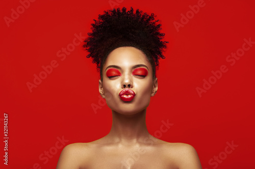 Kiss lips. Share love.Valentine Day. African makeup face. Satisfied Brunette young woman with afro hair style against colorful background.