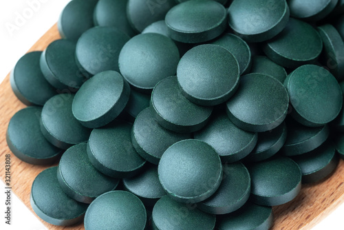 Vitamin and mineral supplements for vegetarians spirulina in tablets in a wooden spoon, close-up. © sergojpg