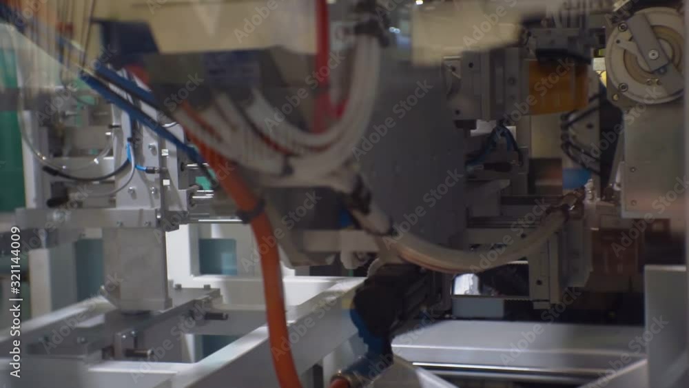 modern manufacturing industry.technological process.production of plastic ware.thermoplastic on an automated line produces plastic cups.close-up.shallow depth of field modern manufacturing industry.technological process.production of plastic ware.thermoplastic on an automated line produces plastic cups.close-up.shallow depth of field
