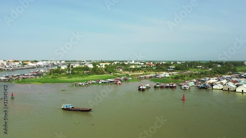 Le village flottant de Chau Doc et un bateau naviguant sur la rivière Bassac éclairés lors d'une jolie journée avec du Soleil dans le delta du Mékong, au sud du Vietnam photo