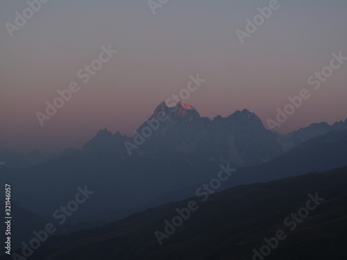 Mountain landscape of Svaneti on bright summer sunny day. Mountain lake, hills covered green grass on snowy rocky mountains background. Caucasus peaks in Georgia. Amazing view on wild georgian nature