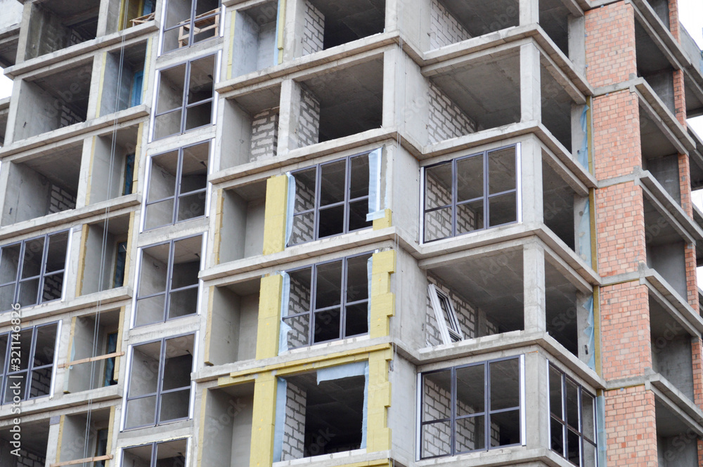 Windows and accessories of a new modern monolithic frame-block house under construction with windows, walls and balconies. Background, texture Windows and accessories of a new modern monolithic frame-block house under construction with windows, walls and balconies. Background, texture