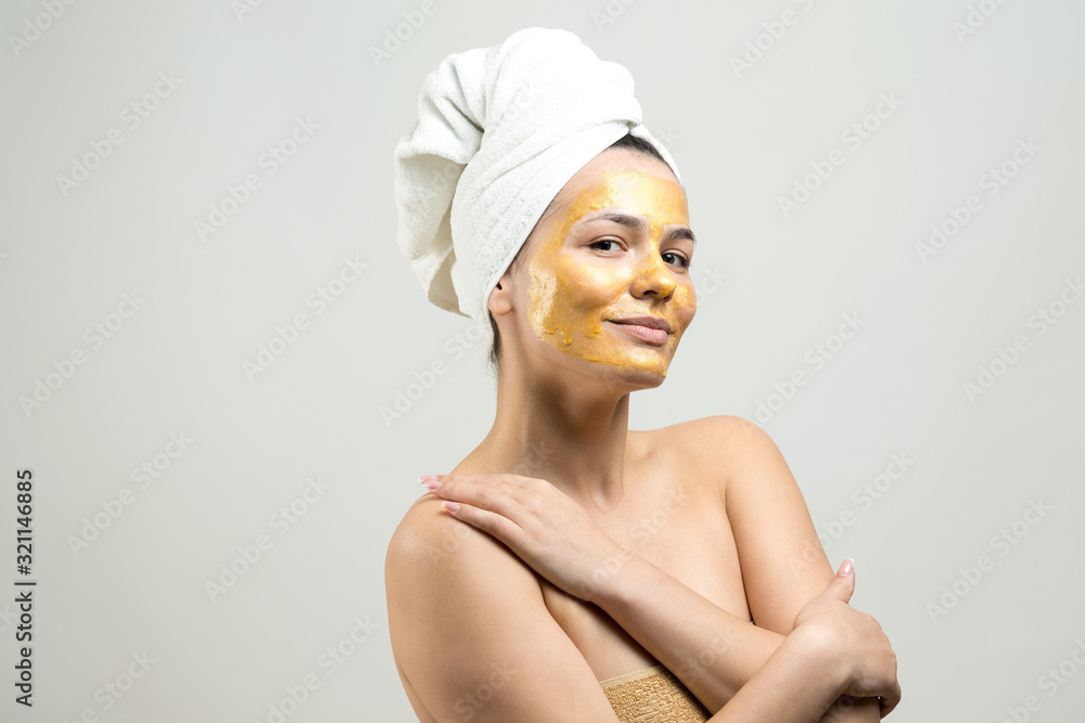 Beauty portrait of woman in white towel on head with gold nourishing mask on face. Skincare cleansing eco organic cosmetic spa relax concept. Beauty portrait of woman in white towel on head with gold nourishing mask on face. Skincare cleansing eco organic cosmetic spa relax concept.