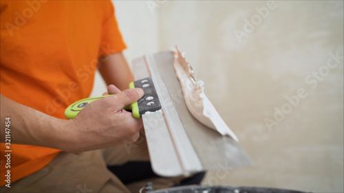 Worker using the trowel for plastering the concrete wall at the construction site. Making the smoothness and flat the surface of cement wall by wooden trowel. Labor day. Worker smoothes a wall using