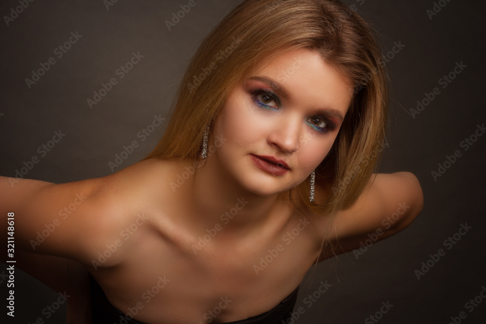 portrait of a blonde on a gray Studio background, in a black dress with sequins portrait of a blonde on a gray Studio background, in a black dress with sequins