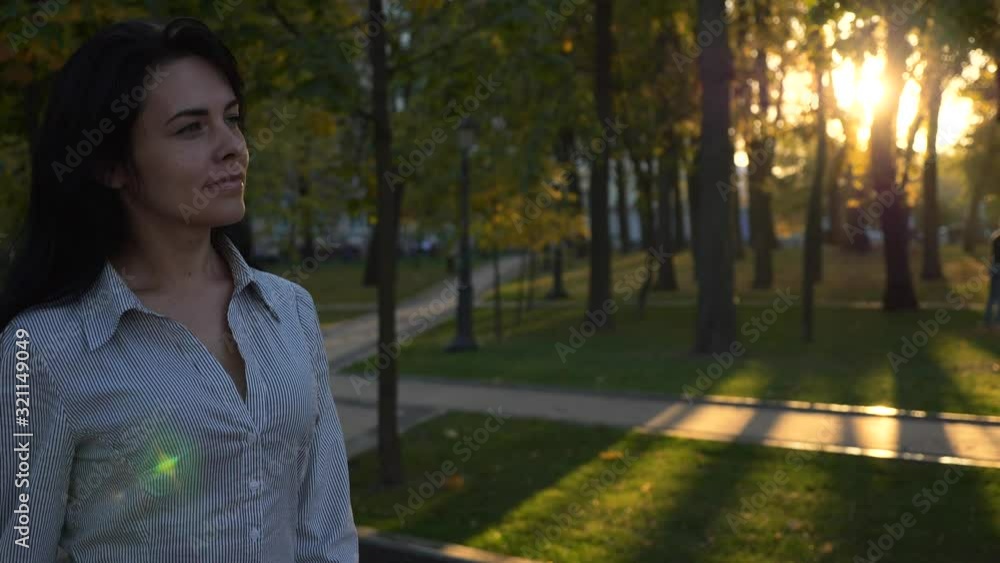 Confident Beautiful Successful Woman Walks In City Park And Thinking. Evening Sunset Background. Autumn Sunny Day In City Park. Lens Flare. Slow motion 4K 60 fps Confident Beautiful Successful Woman Walks In City Park And Thinking. Evening Sunset Background. Autumn Sunny Day In City Park. Lens Flare. Slow motion 4K 60 fps