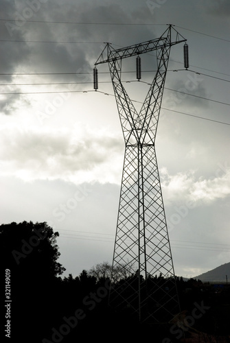 High voltage pylon, in the background dark clouds. Part of high-voltage substation with switches and disconnectors.