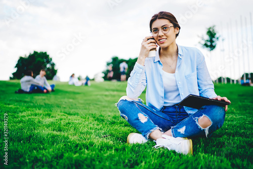 Fotografie Attractive caucasian woman student sitting with coffee to go in park pondering o