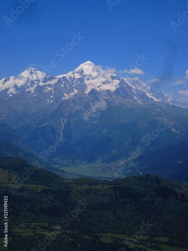 Mountain landscape of Svaneti on bright summer sunny day. Mountain lake  hills covered green grass on snowy rocky mountains background. Caucasus peaks in Georgia. Amazing view on wild georgian nature