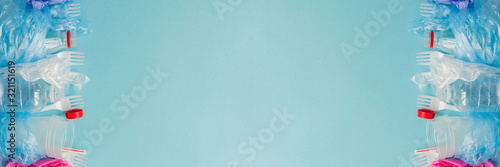 Top view of various kinds of disposable plastic waste on blue background, copy space