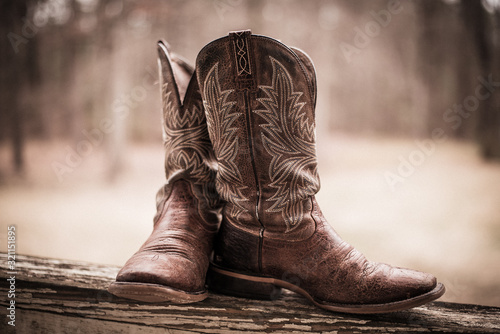 Brown western style boots sitting on a fence in the country 