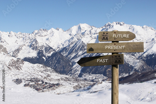 three signs indicating the way to the past, present and future over the mountains covered of snow