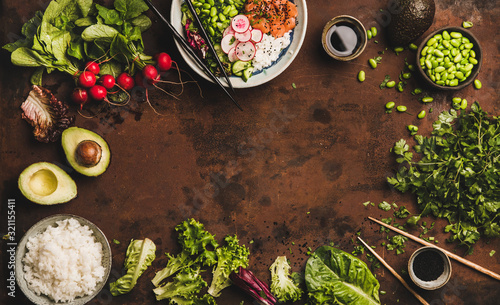 Flat-lay of salmon poke bowl or sushi bowl with vegetables, greens, sushi rice, soy sauce and ingredients over dark rusty table background, top view, copy space. Traditional Hawaiian cuisine