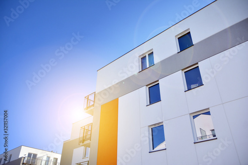 Modern multi story building being lit by the setting sun at afternoon. New apartment house residential building outdoor concept.