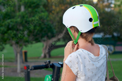 Woman lacing a helmet before a E-scooter ride