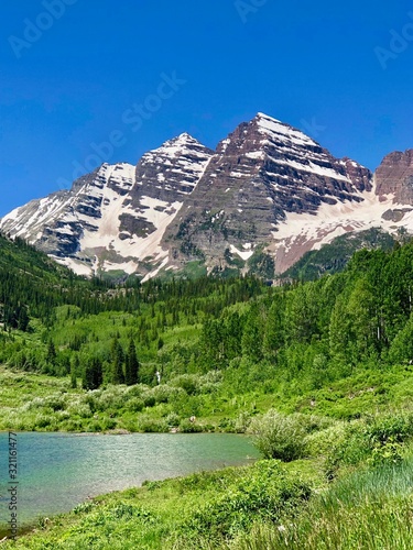 Maroon Bells mountain range turquoise lake and evergreen pine trees and aspens at Maroon Bell Scenic Recreation Area, near Aspen Highlands Ski Area, Colorado Rockies