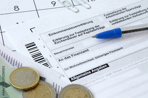 German tax form with pen and european money bills lies on office calendar. Taxpayers in Germany using euro currency to pay taxes photo