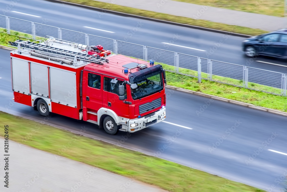 Firefighters during an emergency with protective suits , environmental disaster . Fire engine driving down street
