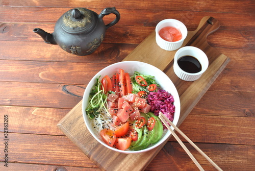 Organic food. Fresh seafood recipe. Tuna poke bowl with crystal noodles, fresh red cabbadge, avocado, cherry tomatoes. Food concept poke bowl on wooden background photo