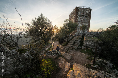 An outdoor woman tourist enjoy the amazing views during sunset of Extremadura countryfields, its woods and Tajo river from the awesome Monfragûe Castle a great defensive position an old Muslim fort
 photo