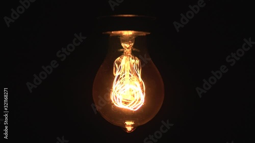 Tungsten light bulb lamp cozy turn on slowly and off over black background, close up shot of old retro vintage light bulb brighten light. Comfort cozy concept. 4k.