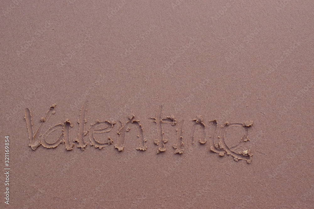 On the sand there is a letter written valentime. On the sand there is a letter written valentime.