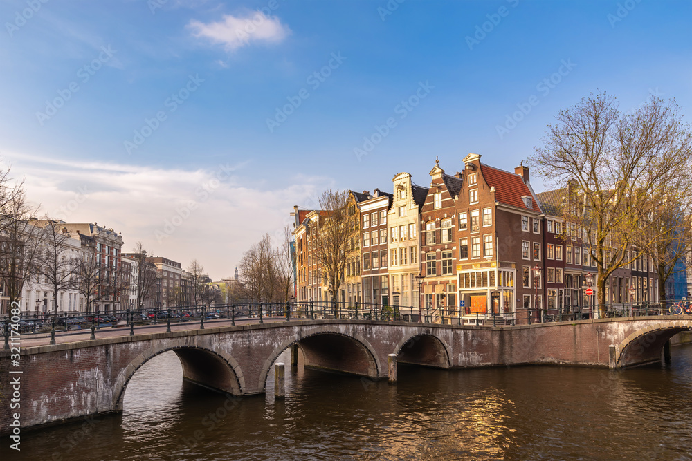 Naklejka premium Amsterdam Netherlands, city skyline at canal waterfront and bridge with traditional house