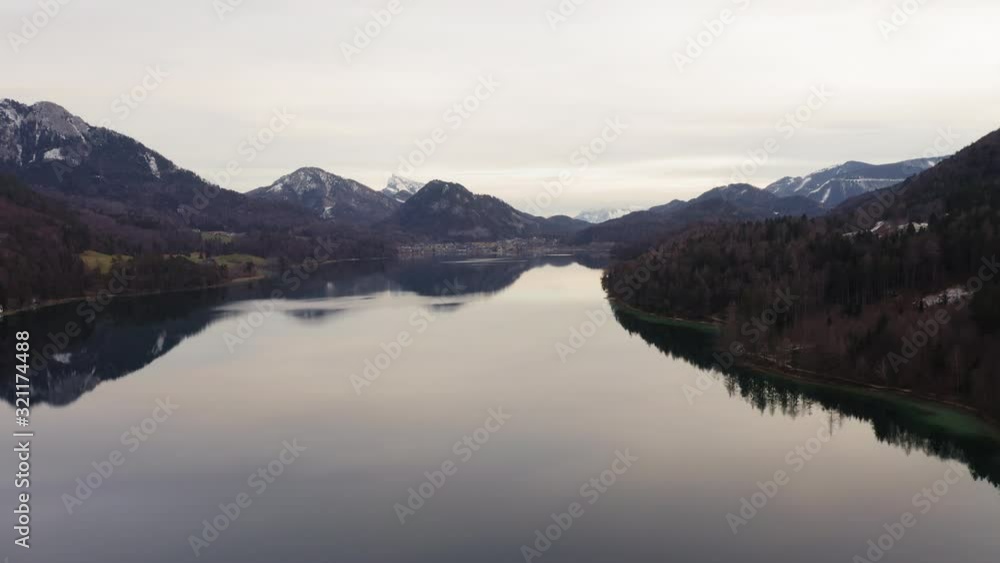 Aerial circling above lake Fuschl surrounded with snowy peaks, Austria