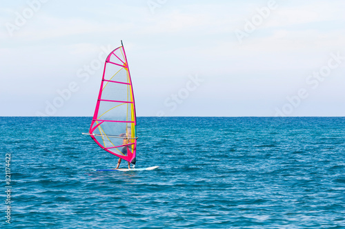 Pink windsurfing sail on the background of the azure sea