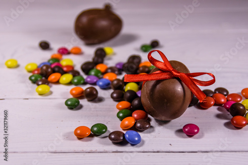 Chocolate easter eggs and multicolored candies on wooden table