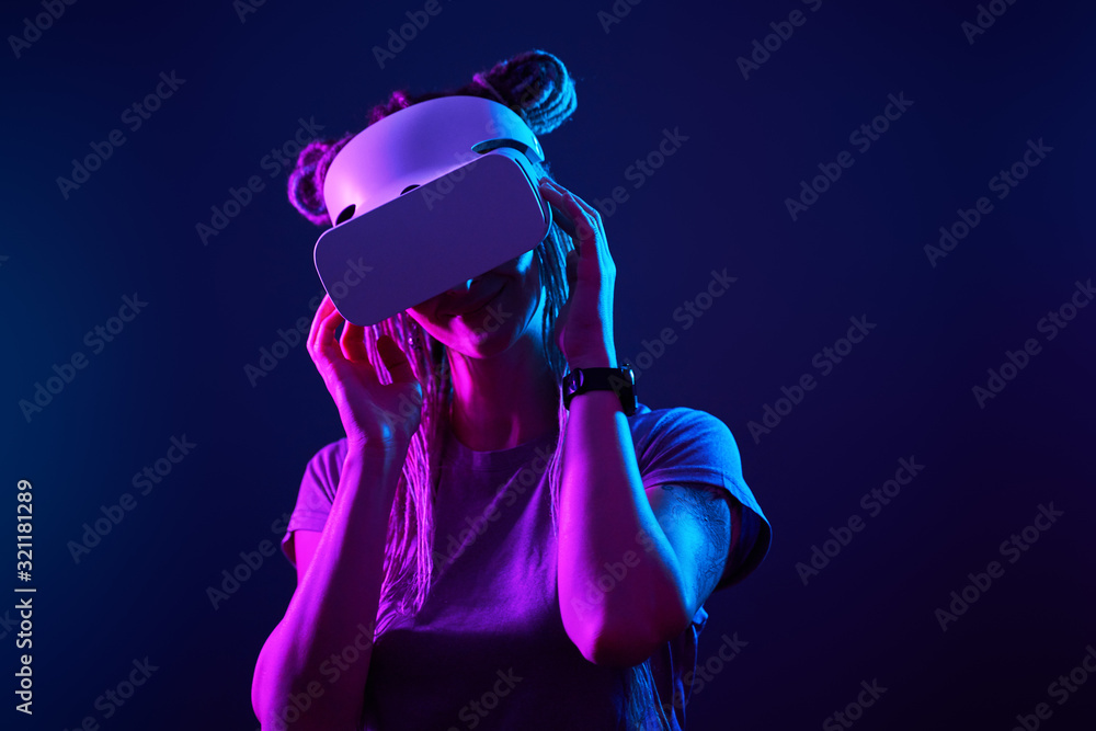 Woman is using virtual reality headset. Neon light studio portrait. Woman is using virtual reality headset. Neon light studio portrait.