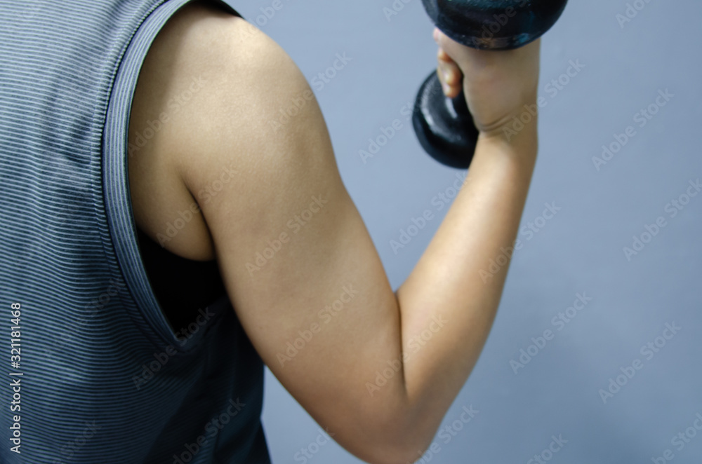 Hand with black dumbbell on gray background. Hand with black dumbbell on gray background.