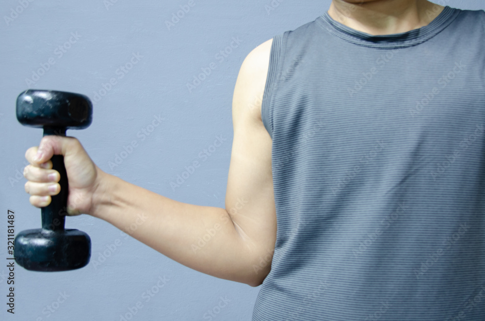 Hand with black dumbbell on gray background. Hand with black dumbbell on gray background.
