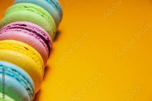Different colorful macaroons on orange background. Free space for text photo