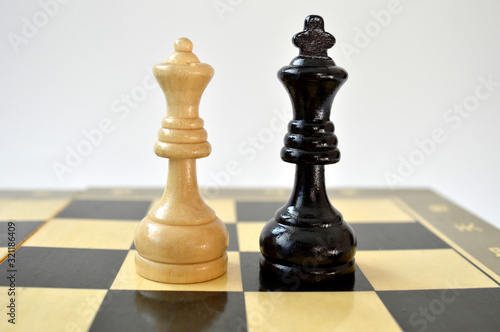 Two chess pieces white queen against black king on the chess board
