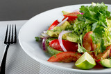 A closeup view of a fresh garden salad, in a restaurant or kitchen setting.