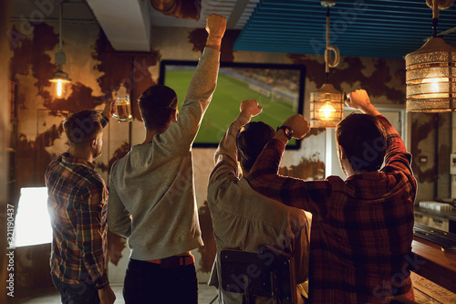 A group of friends watching tv football in a sports bar. © Studio Romantic
