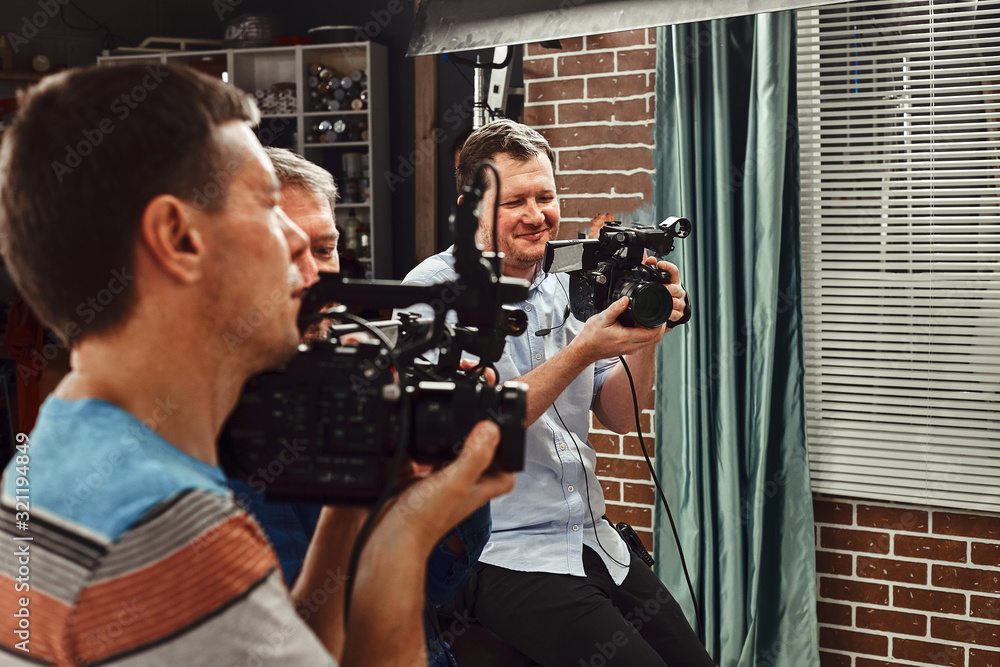 Video production backstage. Behind the scenes of creating video content, a professional team of cameramen with a director filming commercial ads. Video content creation, video creation industry.