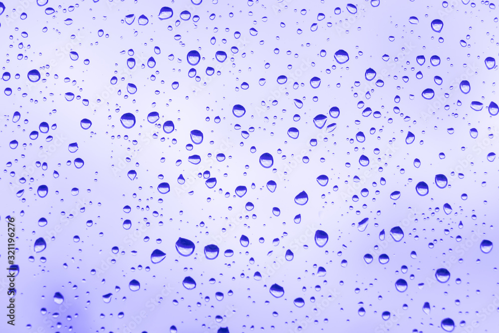 beautiful raindrops on glass window while raining with different texture with violet color blurred background. beautiful raindrops on glass window while raining with different texture with violet color blurred background.