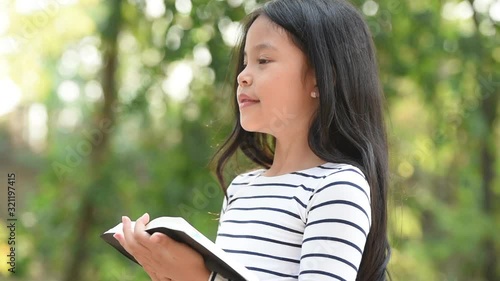 cute little asian girl in reading bible. hands holding on a holy bible. little child girl hands folded in prayer on a holy Bible for faith,spirituality and religion concept.
